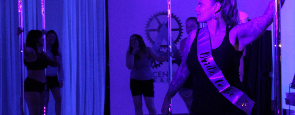 A group of party guests pole dance at the studio